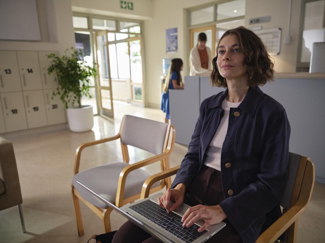 Frau mit Laptop sitzend in einem Warteraum